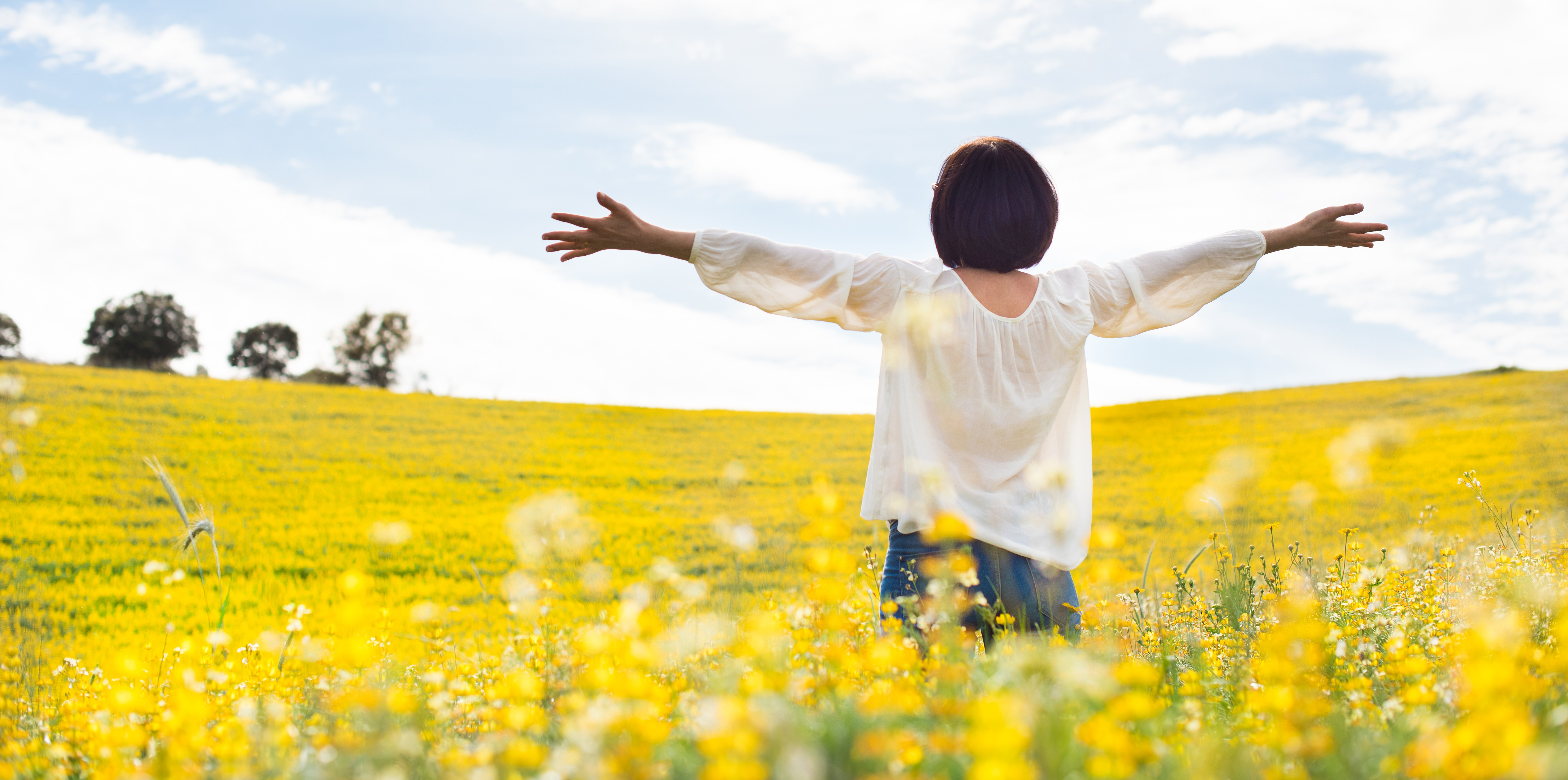 Woman with arms raised in a field of yellow flowers